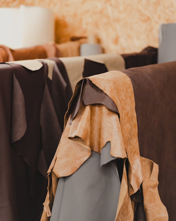 A collection of various tanned leather hides hanging in an indoor setting, showcasing different textures and colors.