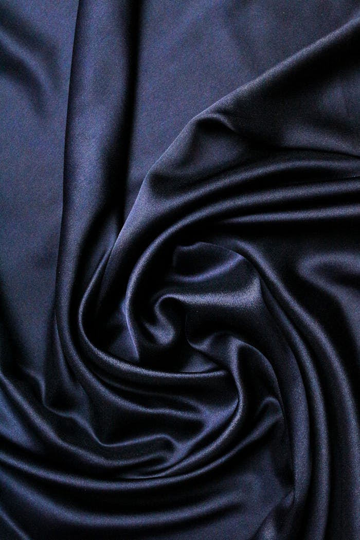 Close-up of luxurious black satin fabric with a swirling texture, perfect for fashion and design uses.