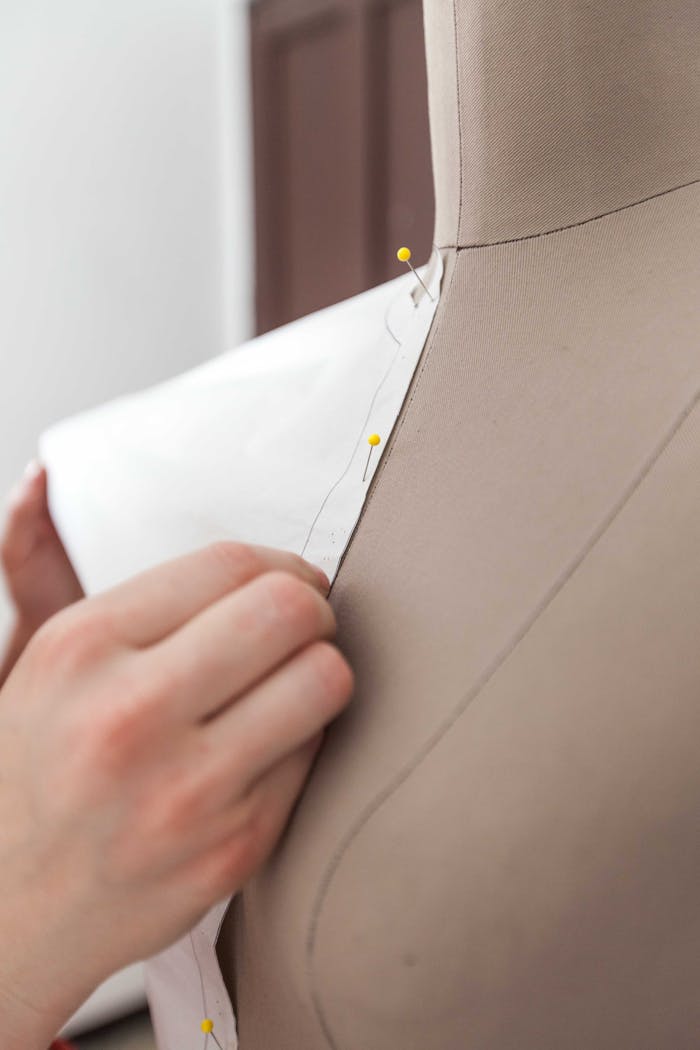 Detailed view of fabric being pinned on a mannequin for dressmaking.